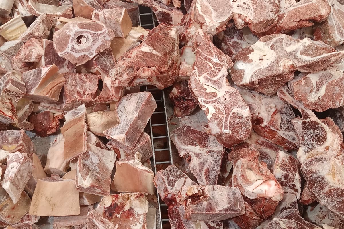 Raw cut beef bones with the marrow exposed, piled on a metal rack